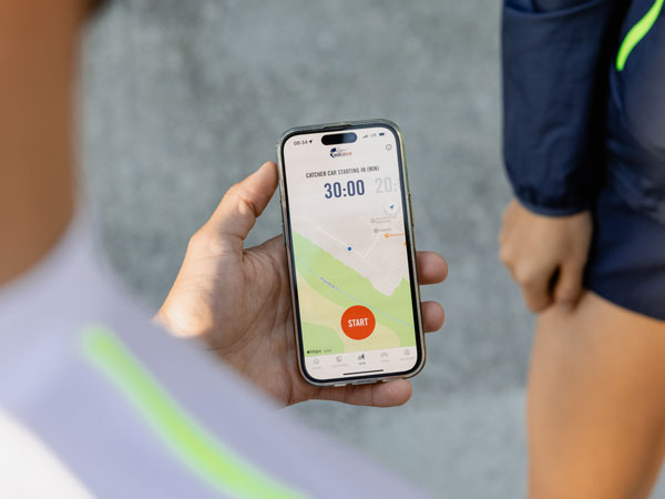 Участник в бягането проверява телефона си, чакайки бягането да стартира.